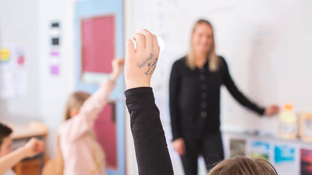 Barn som räcker upp handen framför konsult inom hälsa för elever
