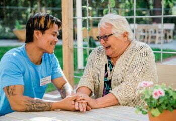 medarbetare och äldre kvinna sitter tillsammans