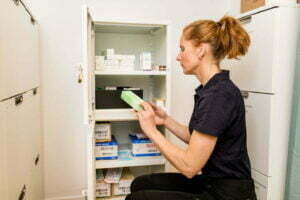 kvinna sitter framför medicinskåp, läser på förpackning