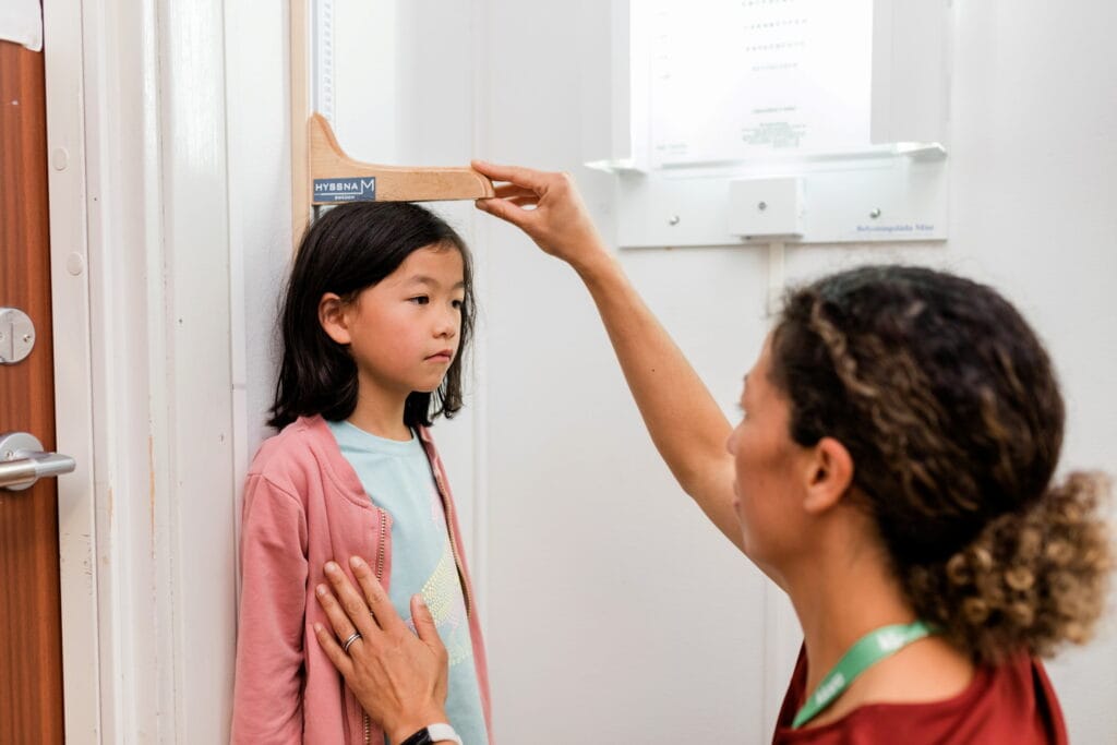 skolsköterska från klara kompetens mäter en flickas längd